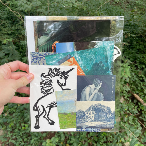 A hand holds a clear plastic sleeve containing a collage of printed art pieces, including a black line drawing of a unicorn, a blue landscape, and a crouching figure, against a background of green foliage.